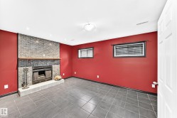 Spacious room featuring a brick fireplace with a wood mantle, tile hearth, and dark grey tile flooring - 