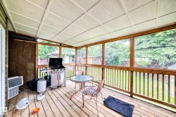 Expansive screened porch featuring wood-finish decking, a white panel ceiling, and wood-framed screen panels - 