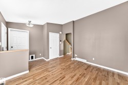 Hardwood flooring throughout a spacious room with light brown walls and white trim - 