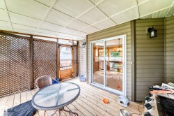 Covered deck with wood-finish flooring and a white grid-pattern ceiling - 