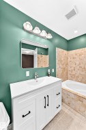 Bathroom featuring a white vanity with an integrated sink, brushed nickel faucet, and matte black hardware - 