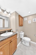 Bathroom featuring a wood-finish vanity with a built-in sink, a wall-mounted mirror, and a three-light fixture - 
