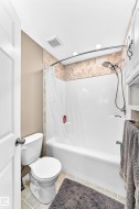 Full bathroom featuring a tub/shower combination with a textured tile surround, a curved shower rod, and recessed lighting - 