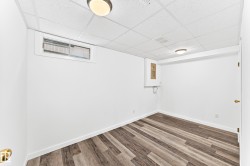 Room featuring wood-finish flooring, white baseboards, and a drop ceiling - 