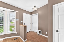 Entryway featuring bay windows with blinds, wood-finish flooring, and terracotta-toned tile - 