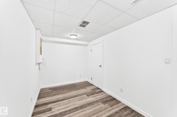 Room with wood-finish flooring, white walls, and a drop ceiling - 