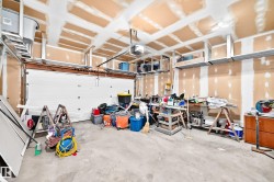 Spacious garage featuring a concrete floor, exposed ceiling joists, and multiple overhead storage racks - 
