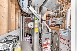 Mechanical room featuring a water heater, furnace, and exposed framing - 