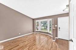 Living space featuring wood-finish flooring, a bay window with blinds, and neutral wall tones - 