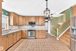 Kitchen featuring light wood cabinetry, stainless steel appliances, and a mosaic tile backsplash - 