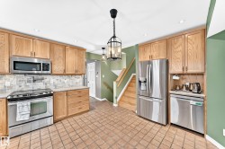 Kitchen featuring stainless steel appliances, light wood-finish cabinetry, tile flooring, and a decorative backsplash - 