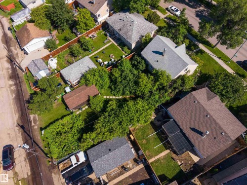 Aerial perspective featuring a property with a brown shingle roof, solar panels, a green lawn, and mature trees - 12943 Sherbrooke Avenue, Edmonton, AB 
