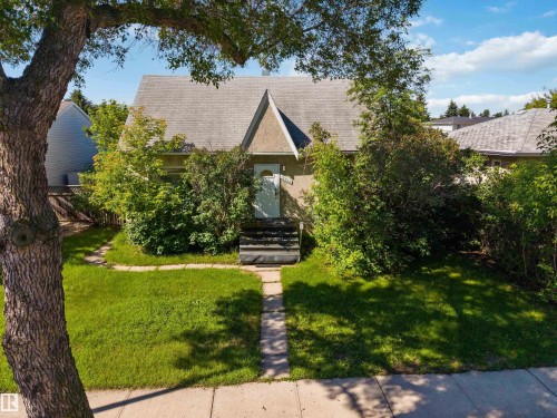 Front exterior featuring a gabled roofline, light-colored stucco siding, and mature landscaping - 12943 Sherbrooke Avenue, Edmonton, AB 