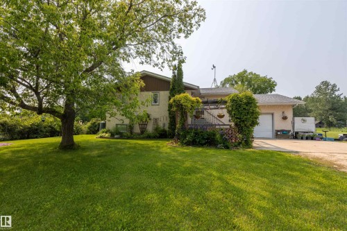 Spacious exterior featuring a stucco facade, attached garage with white door, and an upper-level deck - 59228 Rg Rd 11, Rural Westlock County, AB 