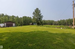 Expansive green lawn with a brown metal-sided building featuring two large garage doors - 
