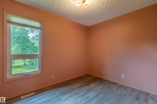 Windowed room featuring wood-finish flooring, a contemporary ceiling light fixture, and a neutral wall color - 59228 Rg Rd 11, Rural Westlock County, AB 