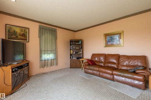 Carpeted room featuring peach-toned walls with a decorative border and a window with sheer curtains - 59228 Rg Rd 11, Rural Westlock County, AB 