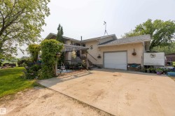 Stucco exterior featuring an attached garage with a white overhead door, an exterior staircase, and a pergola-covered patio - 