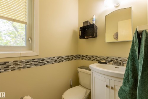 Bathroom featuring a white vanity with a porcelain sink, a wall-mounted mirror, and a window with blinds - 59228 Rg Rd 11, Rural Westlock County, AB 