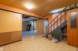Lower level space featuring patterned tile flooring and a painted staircase with wood banister - 