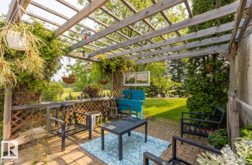 Patio area featuring a wood pergola, brick paver flooring, and a decorative lattice fence - 59228 Rg Rd 11, Rural Westlock County, AB 