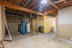 Unfinished basement featuring exposed wood beams and concrete flooring - 