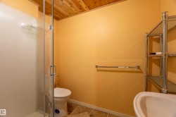 Full bathroom featuring a glass-enclosed shower, a white toilet, and a white pedestal sink - 