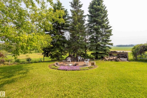 Expansive green lawn featuring a circular stone patio with a central fire pit - 59228 Rg Rd 11, Rural Westlock County, AB 