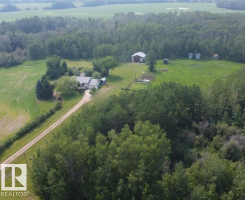 Rural property featuring a main residence, an outbuilding with a red roof, and multiple grain silos, all surrounded by extensive green spaces and mature trees - 59228 Rg Rd 11, Rural Westlock County, AB 