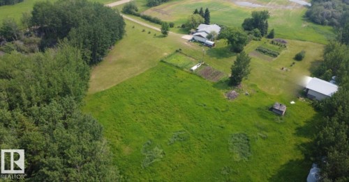 Expansive green acreage featuring a single-story dwelling, multiple outbuildings, and cultivated garden plots - 59228 Rg Rd 11, Rural Westlock County, AB 
