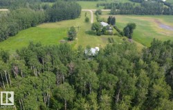 Expansive rural property featuring multiple structures and diverse vegetation - 