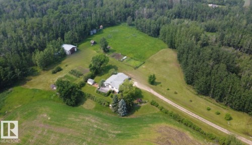 Aerial perspective showcasing a single-family residence with an expansive yard, surrounded by mature trees - 59228 Rg Rd 11, Rural Westlock County, AB 