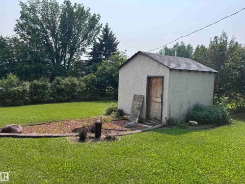 Detached utility building featuring a wood-panel door and textured stucco exterior - 59228 Rg Rd 11, Rural Westlock County, AB 