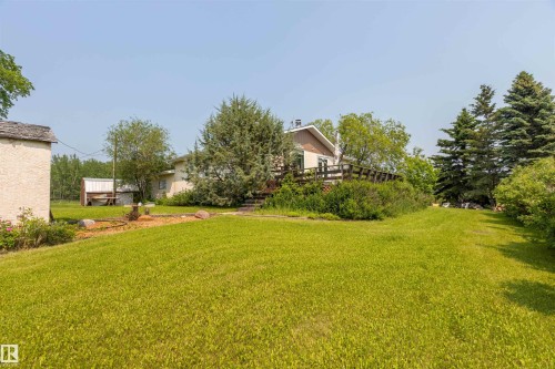 Expansive lawn area with mature trees and a multi-level wooden deck - 59228 Rg Rd 11, Rural Westlock County, AB 