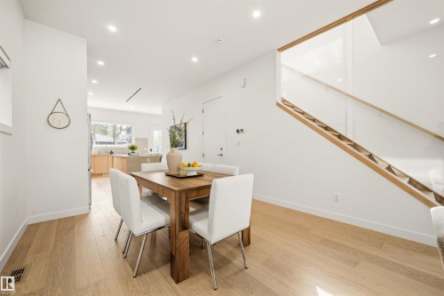 Open-concept interior featuring light wood-finish flooring, recessed lighting, and a modern staircase with clear panel railing - 14037 104 Avenue, Edmonton, AB - Indoor Photo Showing Dining Room