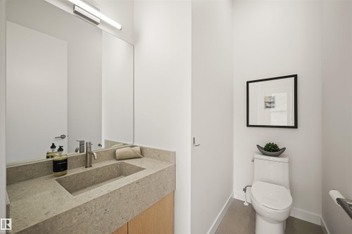 Modern powder room featuring a floating wood-finish vanity, integrated stone sink and countertop, and a wall-mounted rectangular mirror with linear lighting - 14037 104 Avenue, Edmonton, AB - Indoor Photo Showing Bathroom