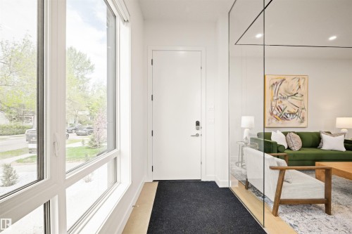 Entryway featuring a white door with contemporary hardware, wood-finish flooring, and a full-height window with white framing - 14037 104 Avenue, Edmonton, AB - Indoor Photo Showing Other Room