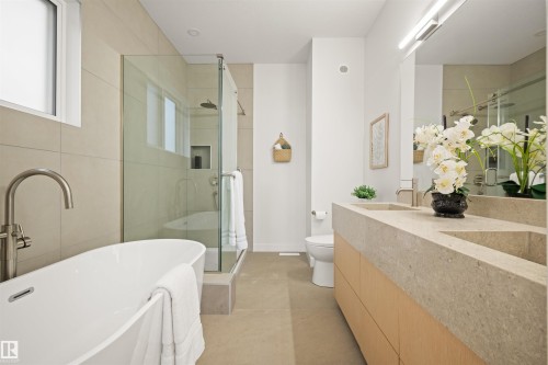 Contemporary bathroom featuring a freestanding soaking tub, a frameless glass shower enclosure, a dual basin vanity with integrated sinks, a floating light wood-finish vanity cabinet, and large-format wall tile - 14037 104 Avenue, Edmonton, AB - Indoor Photo Showing Bathroom