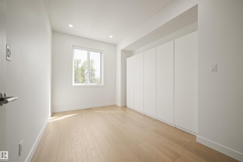 Bright room featuring wood-finish flooring, a white window frame, recessed lighting, and a long wall of built-in white cabinetry - 14037 104 Avenue, Edmonton, AB - Indoor Photo Showing Other Room