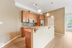 Kitchen featuring wood cabinetry, stainless steel appliances, a subway tile backsplash, and a breakfast bar with pendant lighting - 
