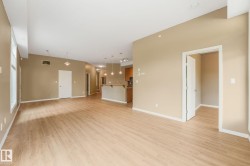 Expansive open-concept living area featuring wood-finish flooring, neutral wall tones, multiple windows, and recessed lighting - 