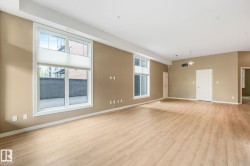 Spacious room featuring wood-finish flooring, two large windows with horizontal blinds, and warm neutral wall paint - 