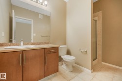 Bathroom featuring a full vanity with wood-finish cabinetry, a stone-finish countertop, and an integrated sink - 