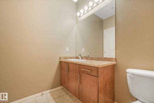 Bathroom vanity with a light wood-finish cabinet, integrated sink, and granite-style countertop - 126 10531 117 Street, Edmonton, AB 