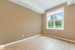 Bright interior space featuring a large window with white framing, wood-finish flooring, and light brown wall tones - 