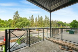 Covered outdoor patio space with concrete flooring, black metal railing, and clear glass panels - 
