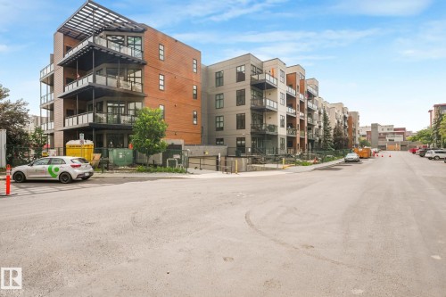 Modern multi-story building featuring brick and panel siding, multiple balconies with glass railings, large windows, and an upper-level pergola structure - 126 10531 117 Street, Edmonton, AB 