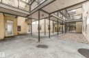 Courtyard entry to property featuring a covered walkway and upper-level glass-paneled balconies - 126 10531 117 Street, Edmonton, AB 