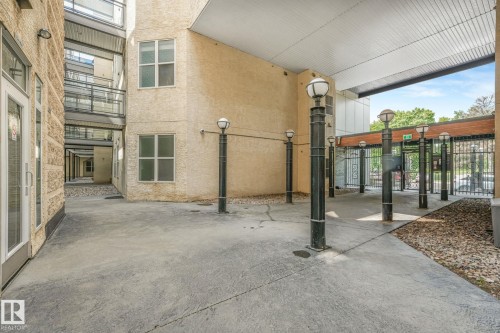 Covered concrete walkway featuring multiple decorative lampposts and secure access gates - 126 10531 117 Street, Edmonton, AB 