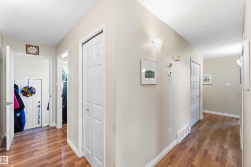 Foyer featuring wood-finish flooring, white trim, and a white six-panel door - 13121 122 Street, Edmonton, AB 